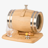 A 3L mini oak aging barrel with a glass window and steel bands, resting on a carved wooden base. The base also holds a whiskey glass and a cigar resting on a steel funnel.