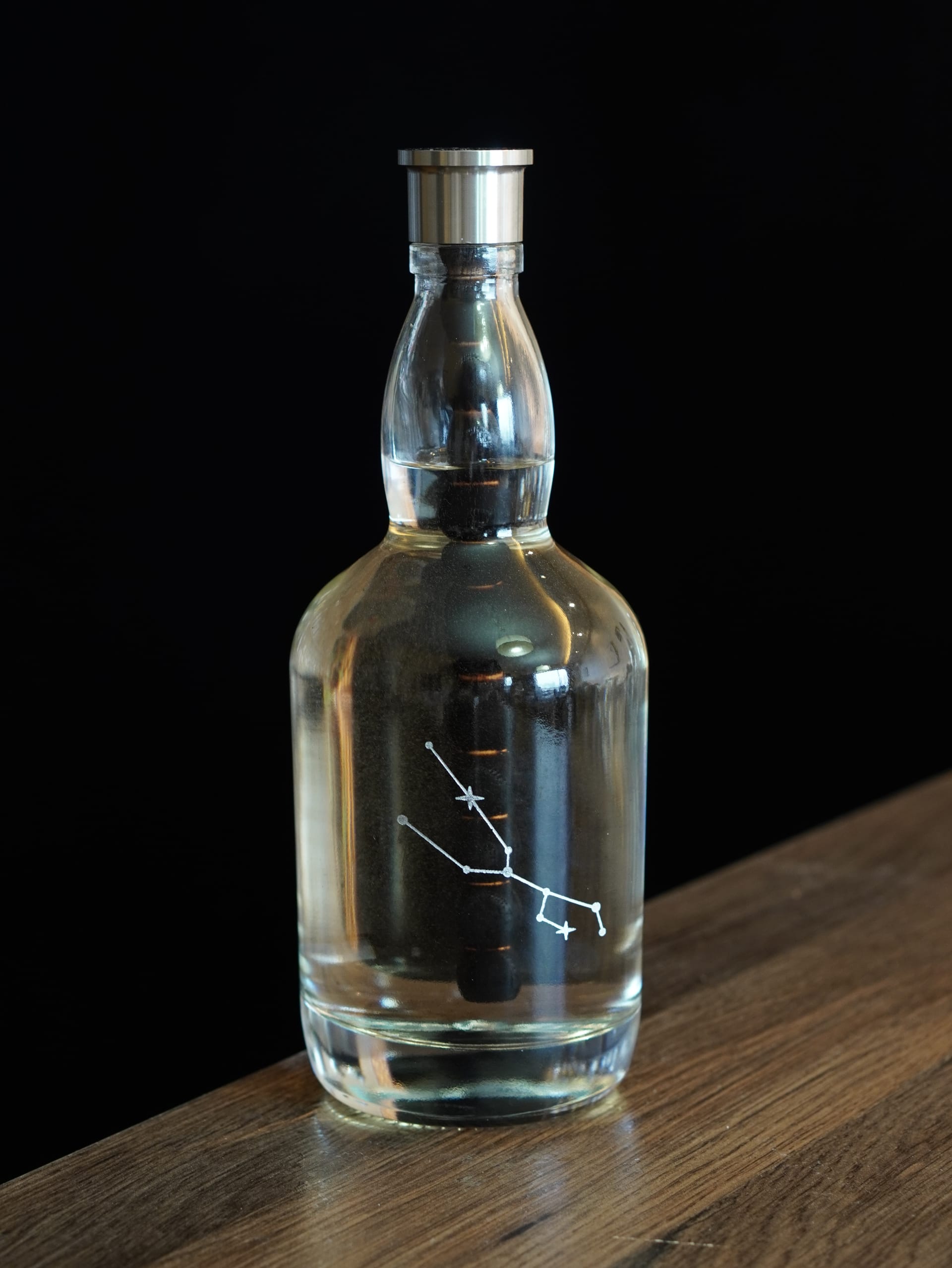 Aging Bottle with constellation engraving on a wooden table