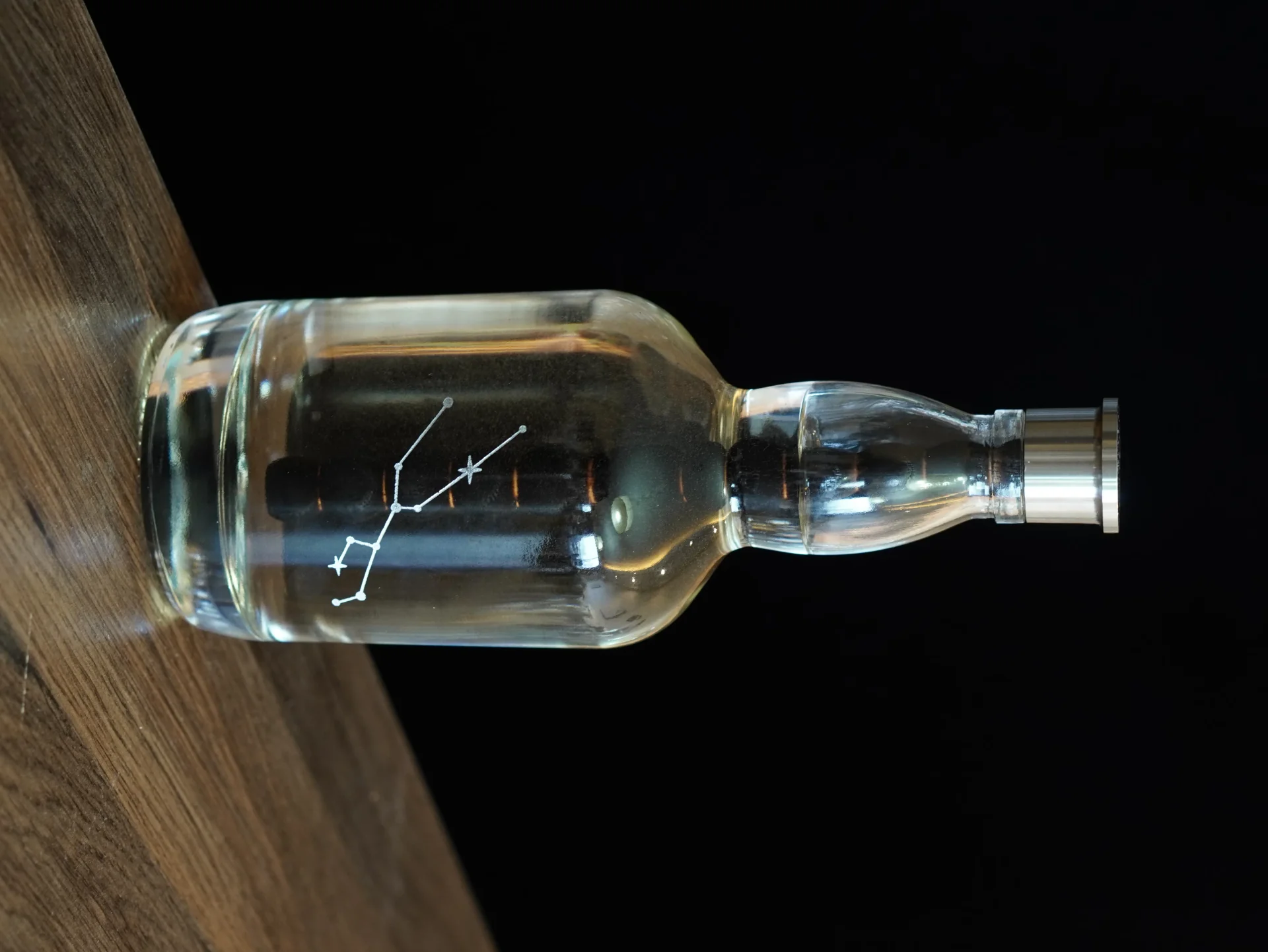 Aging Bottle with constellation engraving on a wooden table