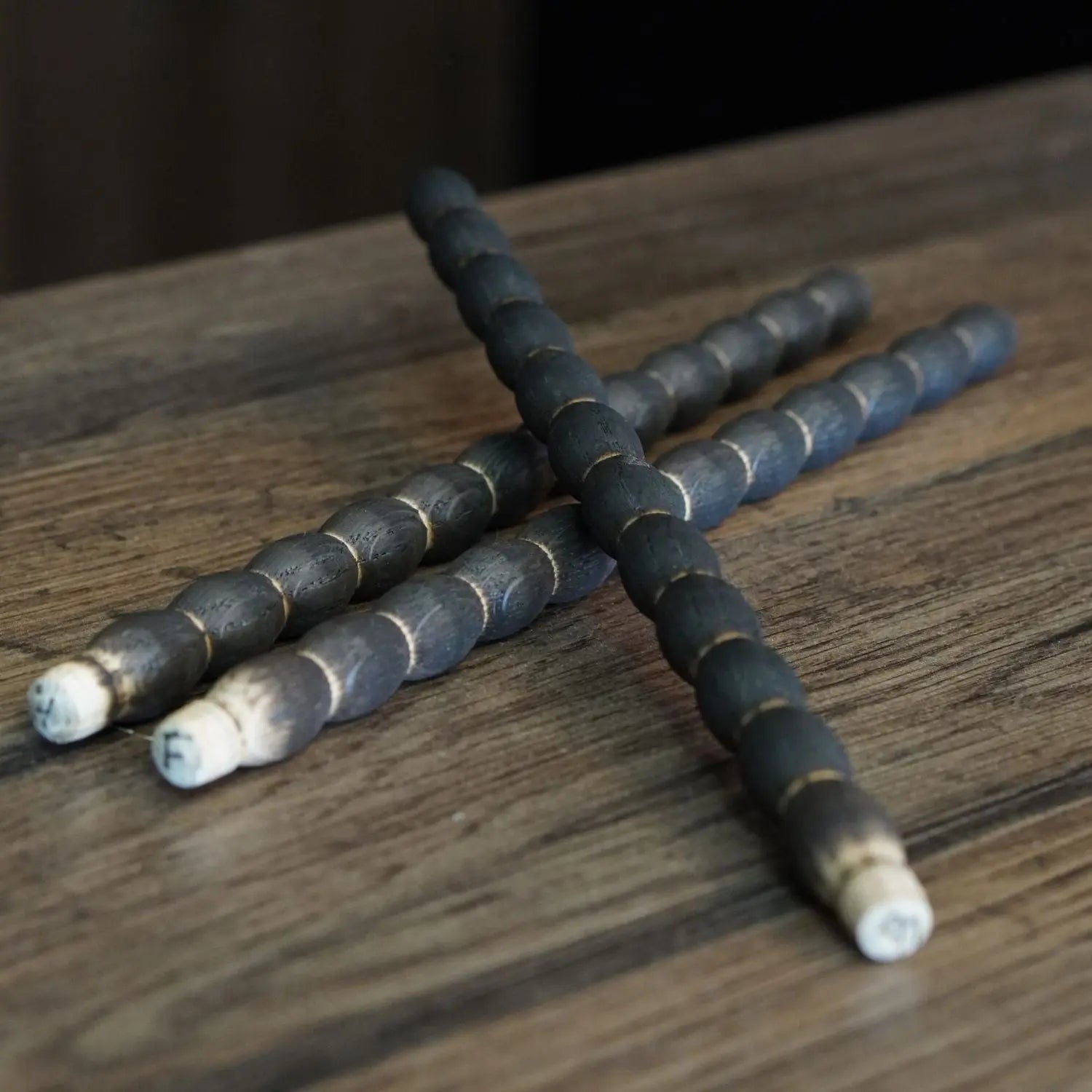 A close-up of three handcrafted, charred oak aging sticks from the whiskey aging kit, showing the detailed texture used to impart flavor into spirits.
